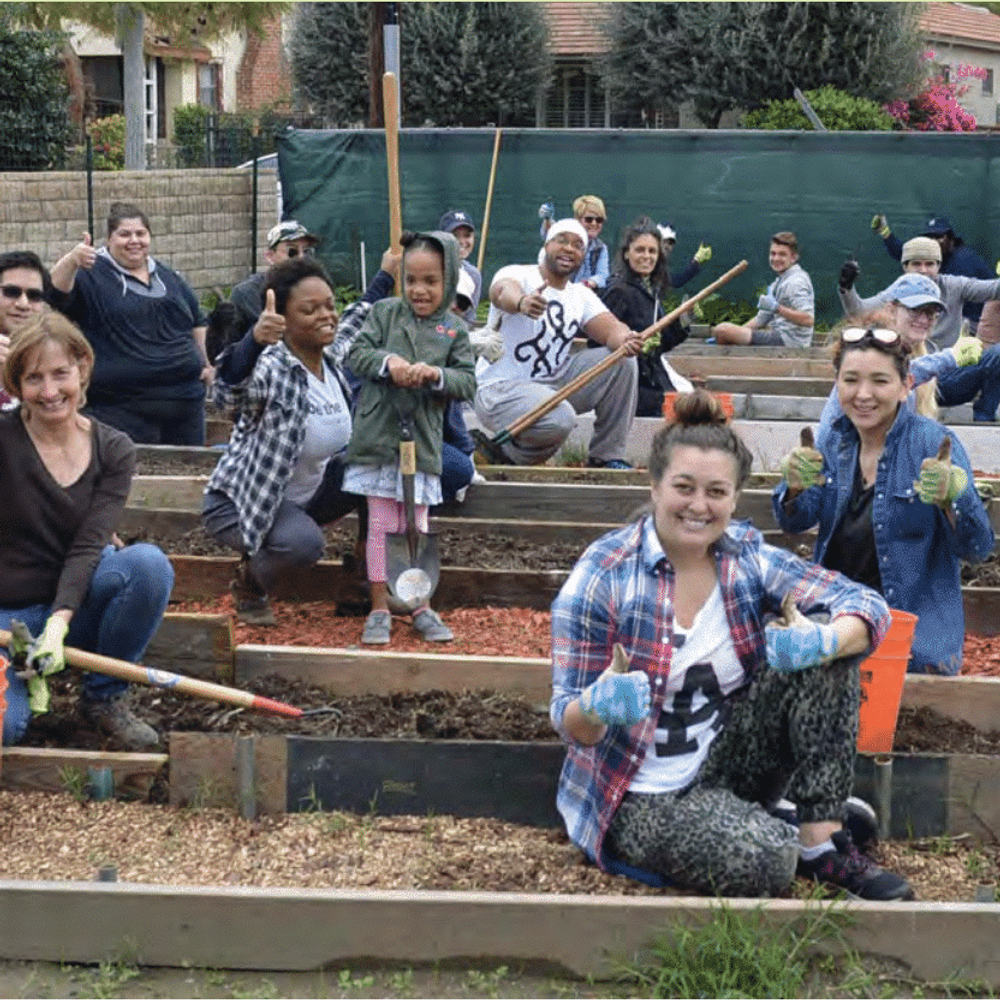 Community members pose for a group photo while tending to a community garden in California