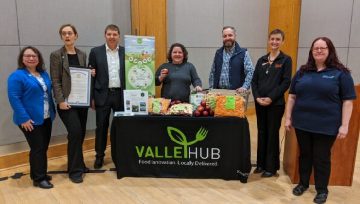 Kalamazoo, Michigan area food systems leaders stand by a ValleyHub table at a celebratory event