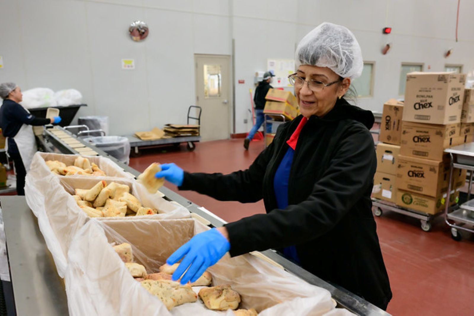 A kitchen staff member prepares bread for serving