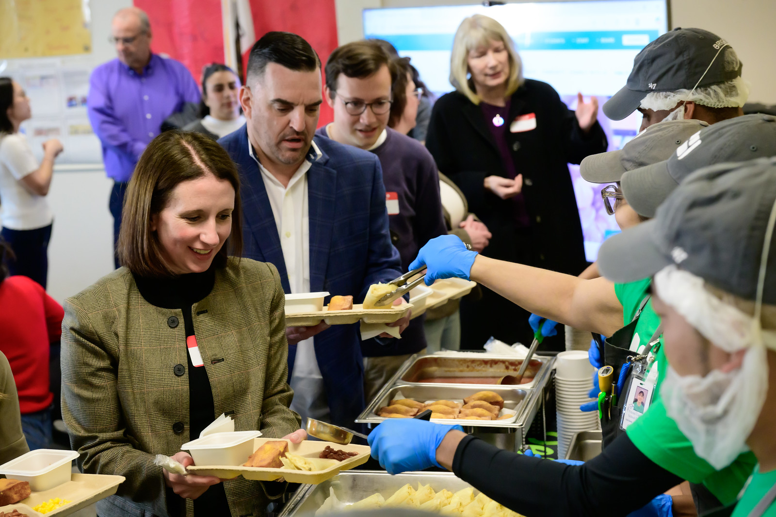 Kitchen staff members serve event guests school lunch