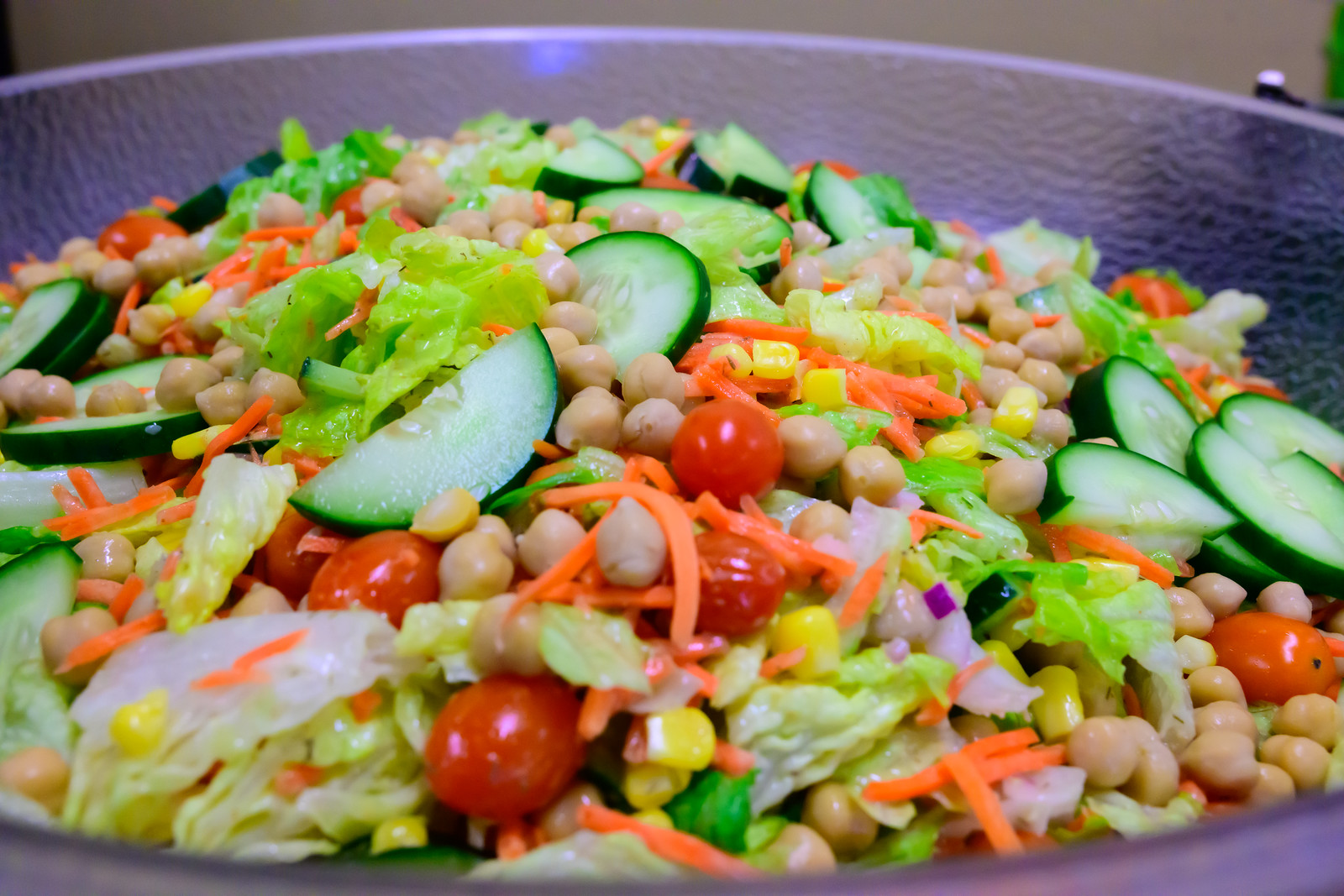 Salad with cucumbers, tomatoes, carrots, corn, lettuce, and chickpeas