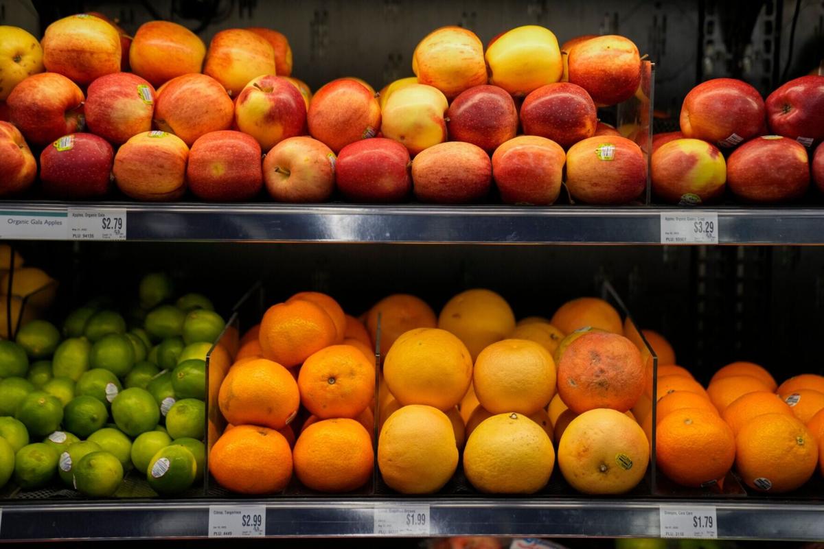 Apples, limes, and oranges on display shelves for sale at a grocery market